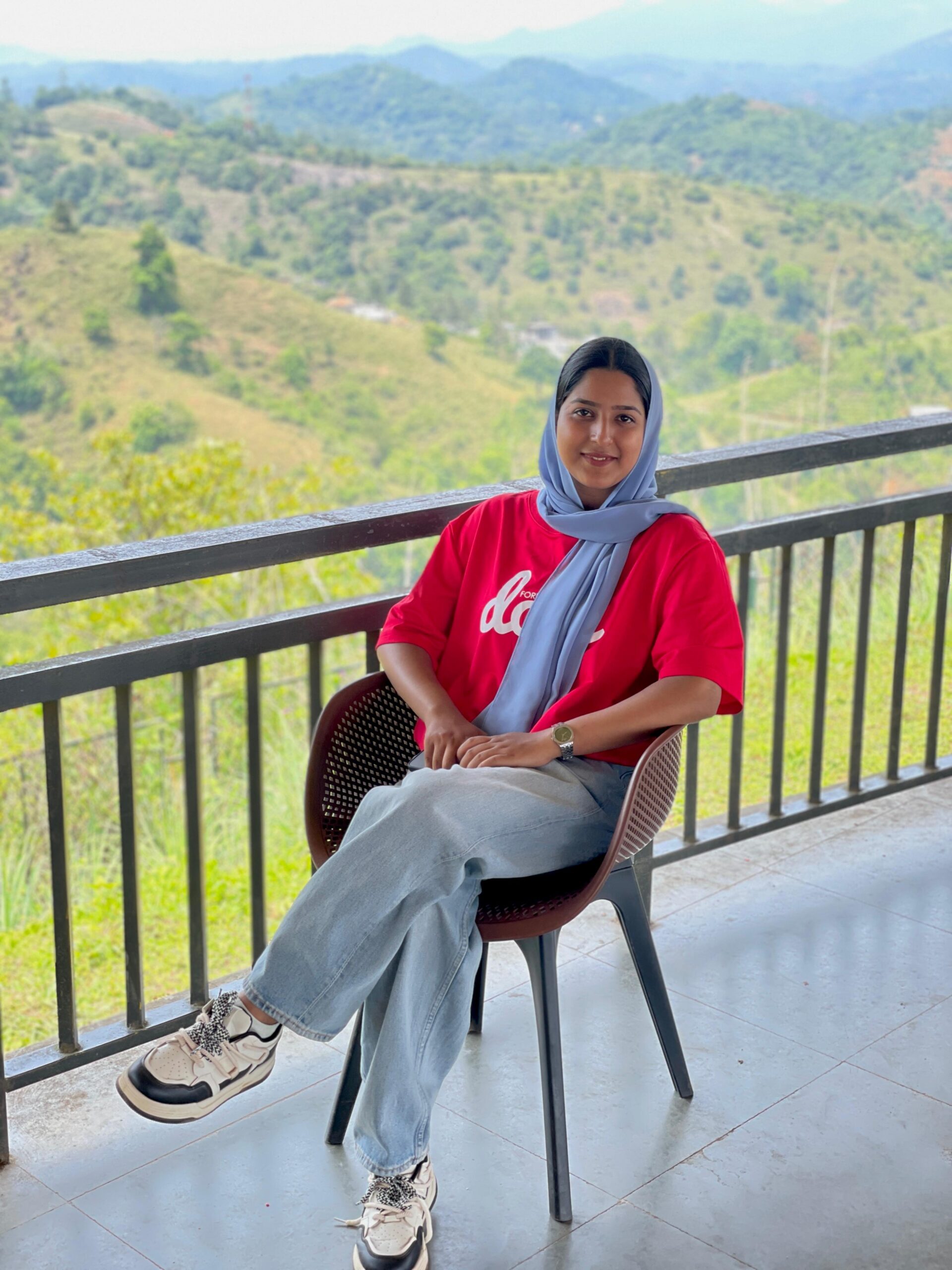 Haneena Sherin sitting on a balcony with a scenic hill view in the background, Best digital marketer in Calicut